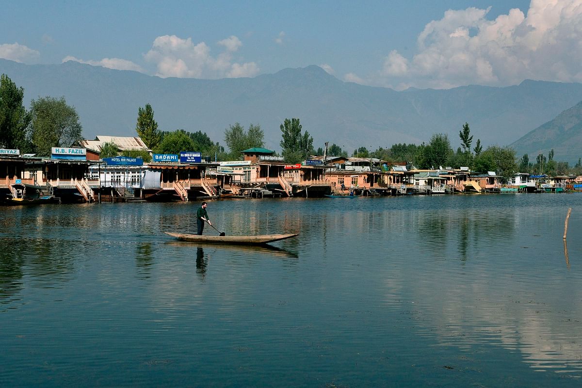 A local man rows a boat near houseboats hotels in Dal Lake in Srinagar on 10 October 2019. Photo: AFP