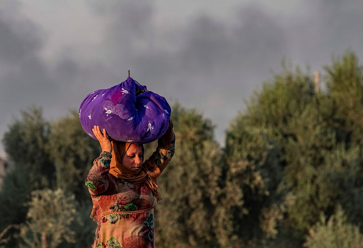 A woman carries her belongings over her head as she flees amid Turkish bombardment on Syria`s northeastern town of Ras al-Ain in the Hasakeh province along the Turkish border on 9 October 2019. Photo: AFP