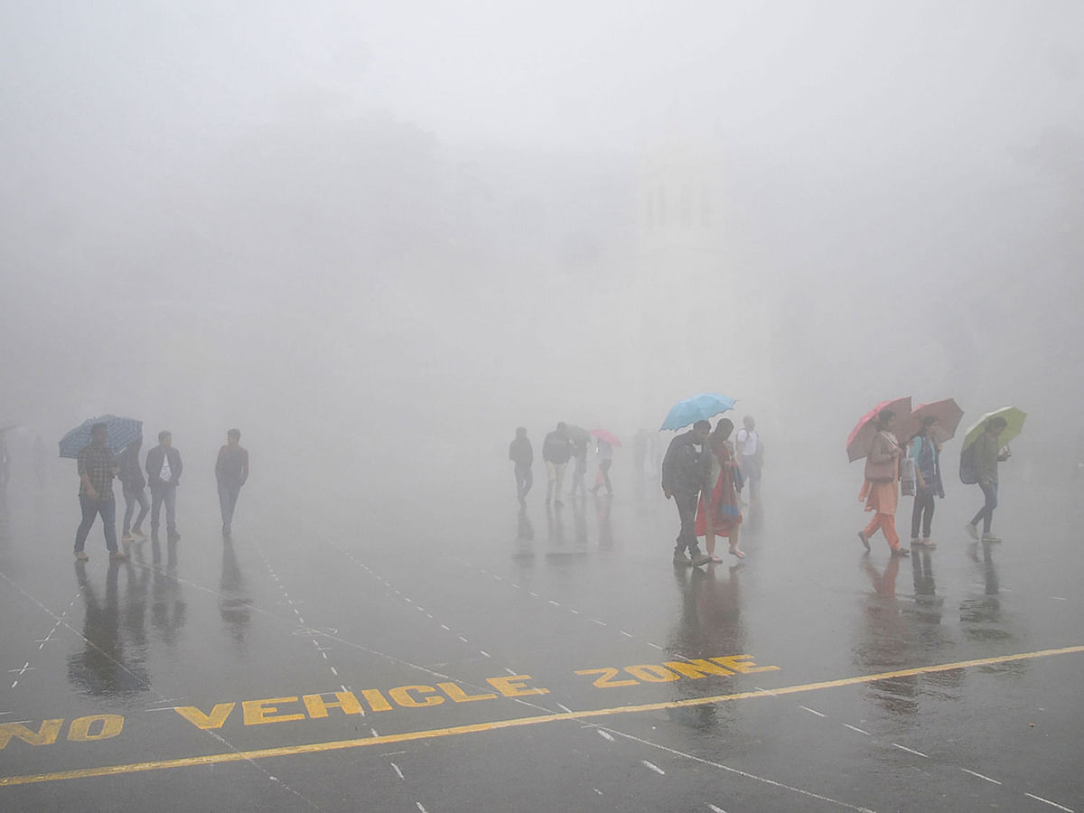 Commuters walk through fog as they hold umbrellas during a rainfall in Shimla in the India`s northern state of Himachal Pradesh on 9 October 2019. Photo: AFP