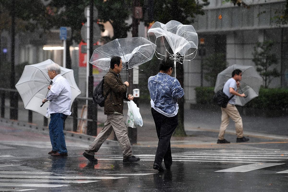 Pedestrians hold onto their umbrellas as rain falls amid strong winds in Tokyo on 12 October 2019, ahead of Typhoon Hagibis` expected landfall in central or eastern Japan later in the evening. Photo: AFP