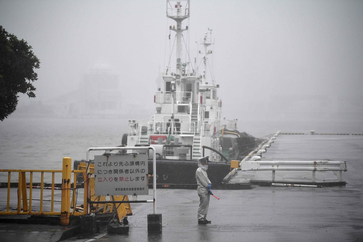 A worker clad in rain gear stands before a pier at Hinode in Tokyo on 12 October 2019, ahead of Typhoon Hagibis` expected landfall in central or eastern Japan later in the evening. Photo: AFP