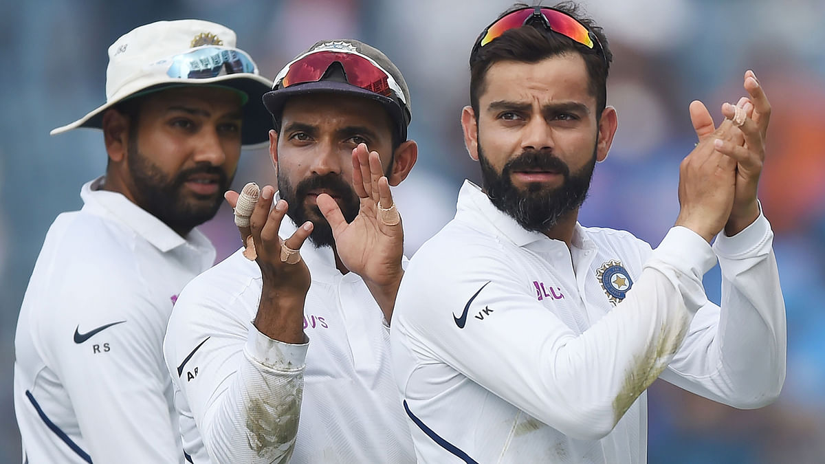 Indian team captain Virat Kohli (R), Ajinkya Rahane (C) and Rohit Sharma gesture towards fans as they celebrate on the fourth day of play after winning the second Test cricket match against South Africa, at the Maharashtra Cricket Association Stadium in Pune on Sunday.