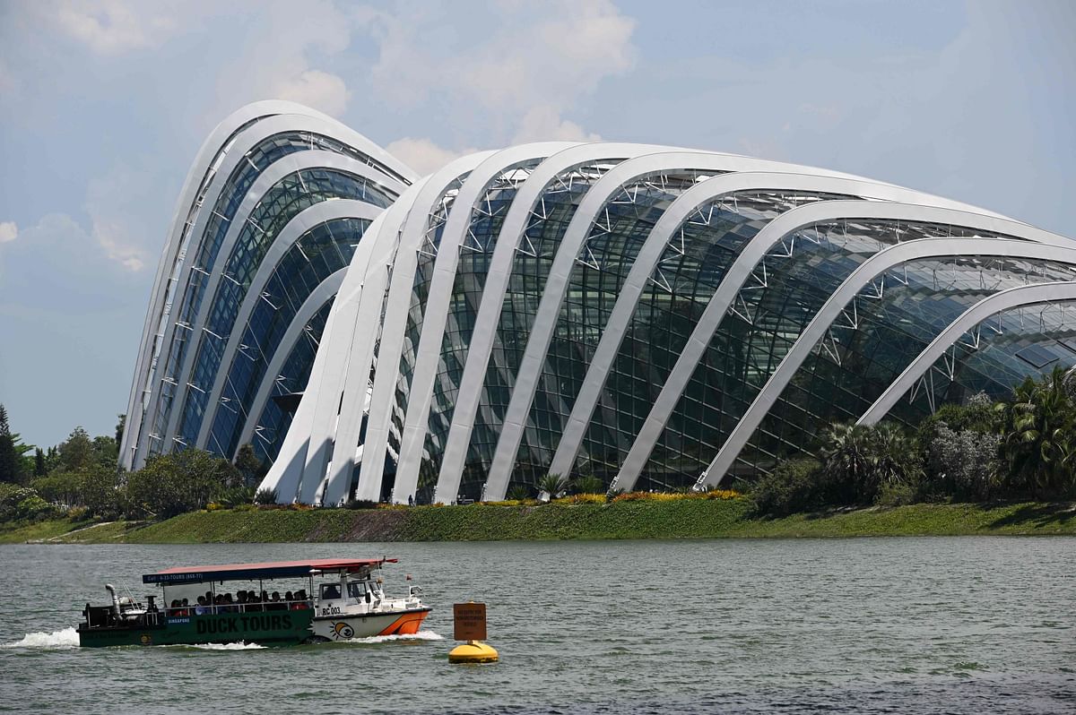 People ride in a tour boat past the Flower Domes of Gardens by the Bay along Marina Bay in Singapore on 11 October 2019. Photo: AFP