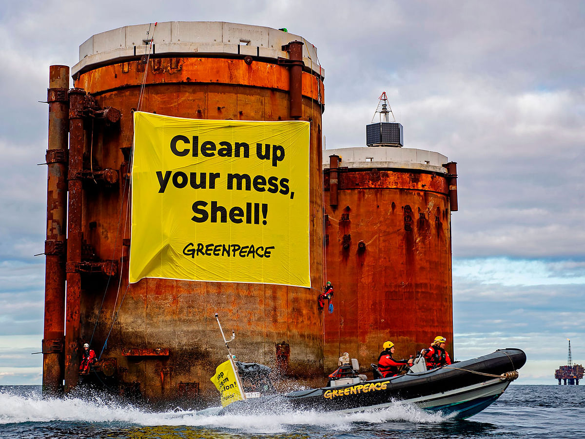In a handout picture received from Greenpeace on 14 October, Greenpeace activists hung banners saying, `Shell, clean up your mess!` and `Stop Ocean Pollution` in a peaceful protest against plans by the company to leave parts of old oil structures with 11,000 tons of oil in the North Sea. Photo: AFP