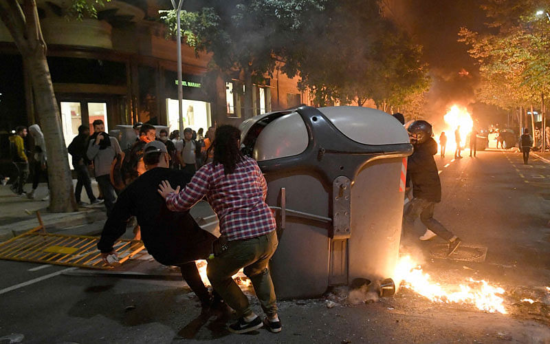 Protesters burn garbage containers during protests in Barcelona on October 15, 2019, as Catalonia geared up for more upheaval a day after thousands of pro-independence activists stormed Barcelona airport in an angry response to Spain’s jailing of nine of its leaders following a failed secession bid.