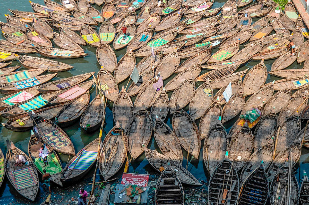 Men walk over boats parked in the Buriganga river in Dhaka on 18 October 2019. Photo: AFP