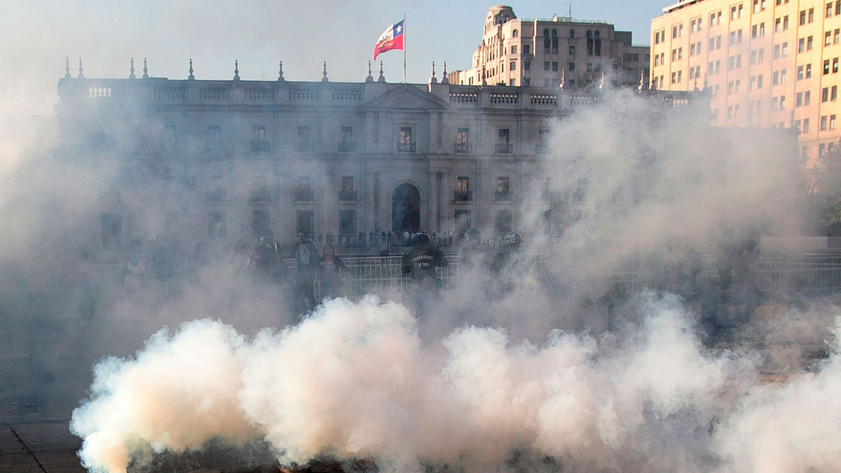 Demonstrators clash with riot police following a mass fare-dodging protest in front of La Moneda palace Santiago, on Friday. School and university students joined a mass fare-dodging protest in Santiago`s metro following the highest fare rise in recent years, paralysing two of it`s main lines. Photo: AFP