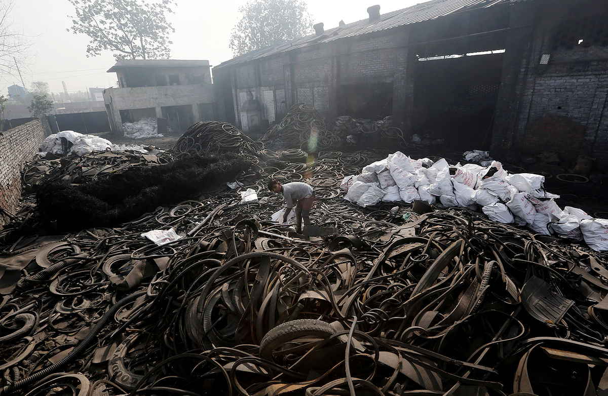A boy scouts for scrap items amidst a pile of used tyres at a pyrolysis unit in Jokhabad. Photo: Reuters