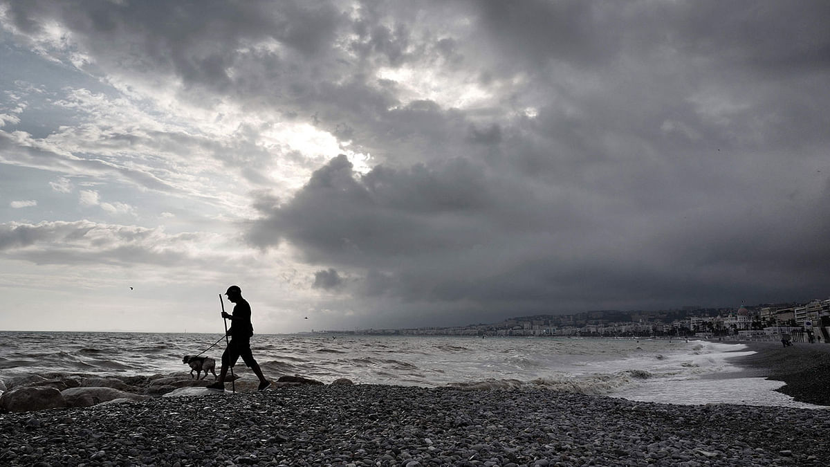 A man walks with his dog on the beach by the Mediterranean sea after heavy rains on the French Riviera city of Nice, southern France, on 19 October 2019. Photo: AFP
