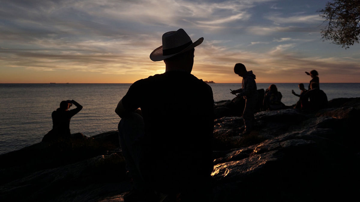 People look at the sunset on the banks of the Rio de la Plata in Colonia del Sacramento, Uruguay, on 19 October 2019. Photo: AFP