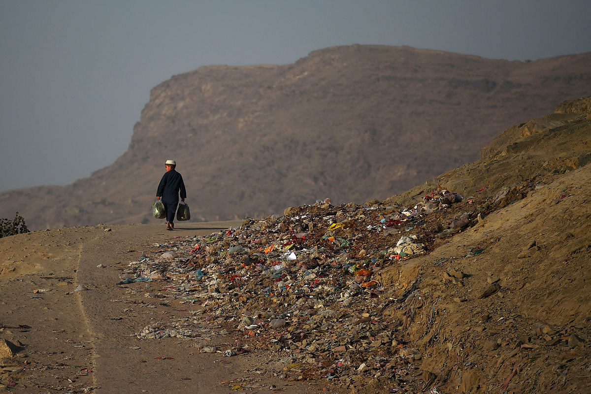 A boy carries grocery bags as he walks along a road on a hillside in Kabul on 17 October 2019. Photo: AFP