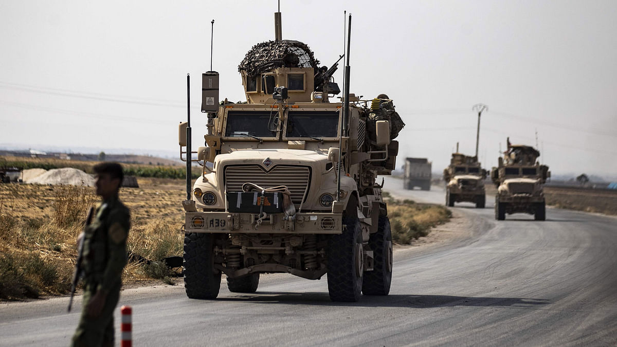 US military vehicleS drive on a road after US forces pulled out of their base in the Northern Syriain town of Tal Tamr on 20 October. Photo: AFP