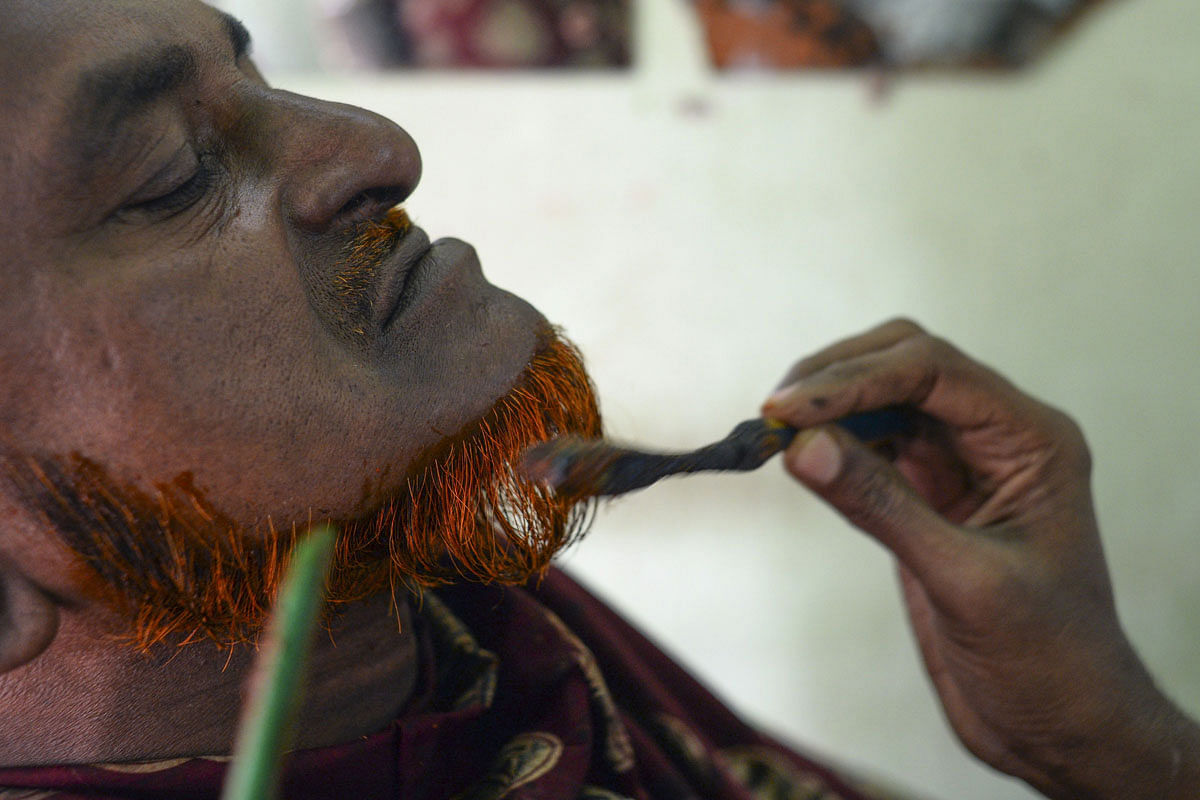 In this photograph taken on 19 January 2019, barber Mohammad Shadat Hossain applies henna to the beard of his client Abdur Rahman (L) in Dhaka. From shades of startling red to hues of vivid tangerine, brightly coloured beards have become a fashion statement on the streets of Bangladesh capital Dhaka. Photo: AFP