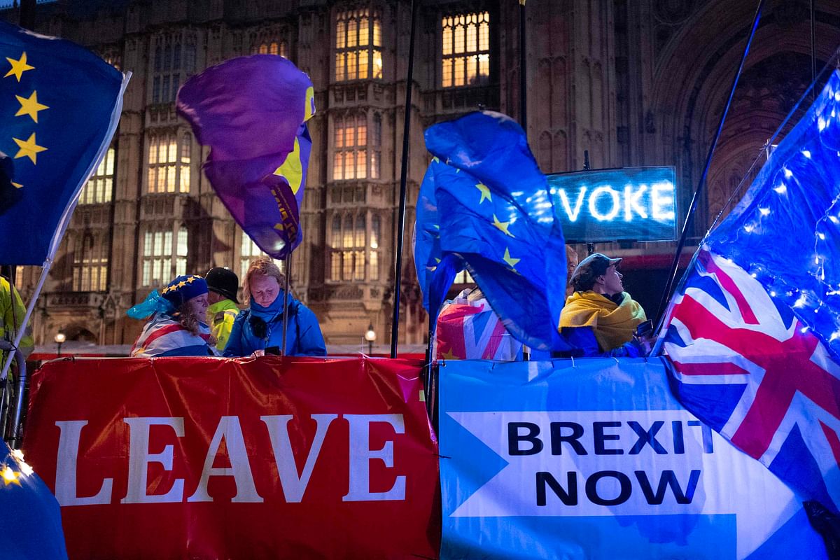 Pro and anti-Brexit aprotesters wave flags and hold banners as they demonstrate outside of the Houses of Parliament in central London on 21 October. Photo: AFP