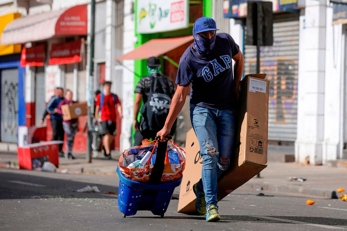 A looter drags stolen goods on the fourth straight day of protests against a now suspended hike in metro ticket prices, in Valparaiso, Chile, on 21 October 2019. Photo: AFP