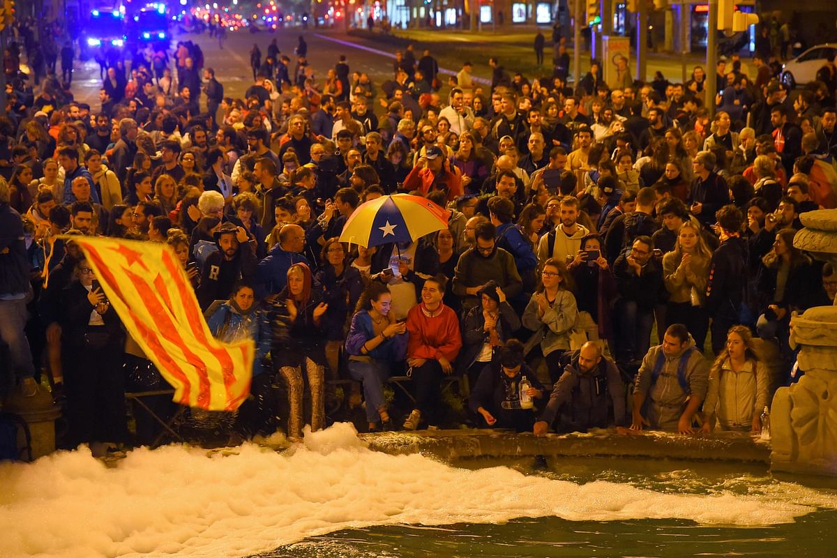Protesters hold a Catalan pro-independence `Estelada` flag and pour soap in a public fountain during a demonstration at the Placa d`Espana square called by the local Republic Defence Committees (CDR) on 22 October in Barcelona. Photo: AFP