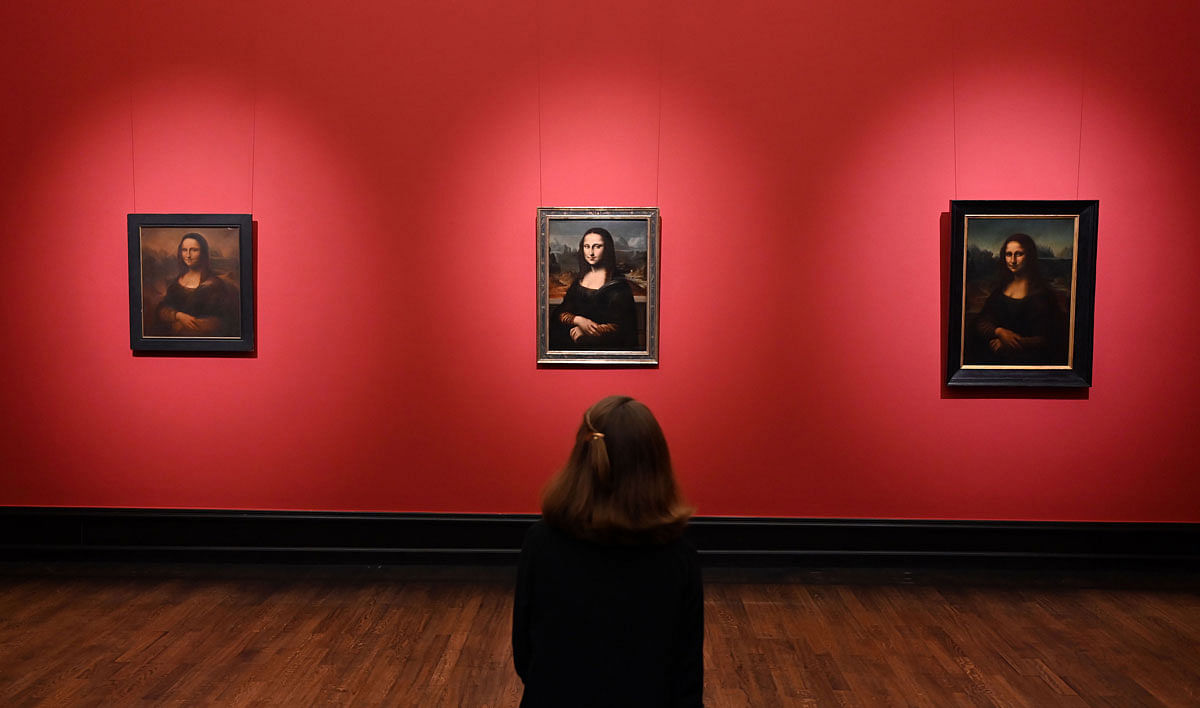 A woman looks at 3 replicas of the Mona Lisa, (L-R) by Angelo di Vincenzo, Mona Lisa, 1926, Anonymous, Mona Lisa, 16/17 century and Carl Velten, `Portrait of the Mona Lisa` 1859, at the exhibition `Icons: Worship and Adoration` at the Kunsthalle Bremen on 17 October 2019. Photo: AFP