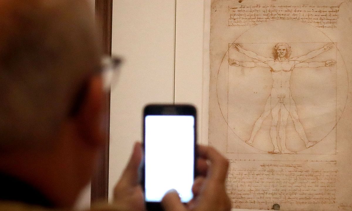 A man looks at the ` Vitruvian Man ` the famous annotated drawing, made around 1490 with pen, ink and wash on paper, by Leonardo da Vinci`s, during the opening of the exhibition ` Leonardo da Vinci `, on 22 October 2019 at the Louvre museum in Paris. Photo: AFP