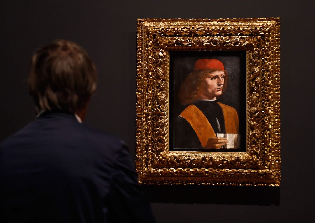 A person looks at an oil on wood painting by Leonardo da Vinci`s ` Portrait of a Musician `, during the opening of the exhibition ` Leonardo da Vinci `, on 22 October 2019 at the Louvre museum in Paris. Photo: AFP
