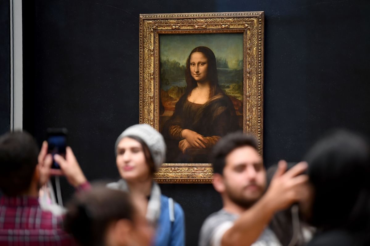 In this file photograph taken on 7 October 2019, visitors take photographs in front of The Mona Lisa (La Gioconda) after it was returned at its place at the Louvre Museum in Paris. Photo: AFP