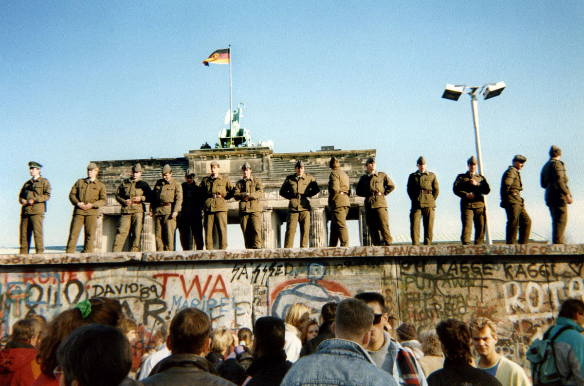 In this file photo taken on 11 November 1989 East German border guards stand on a section of the Berlin wall with the Brandenburg gate in the background in Berlin. For nearly three decades the forbidding Berlin Wall separated communist East Germany from the West, becoming the emblem of the post-World War II split of Europe into Soviet and Western spheres. Photo: AFP