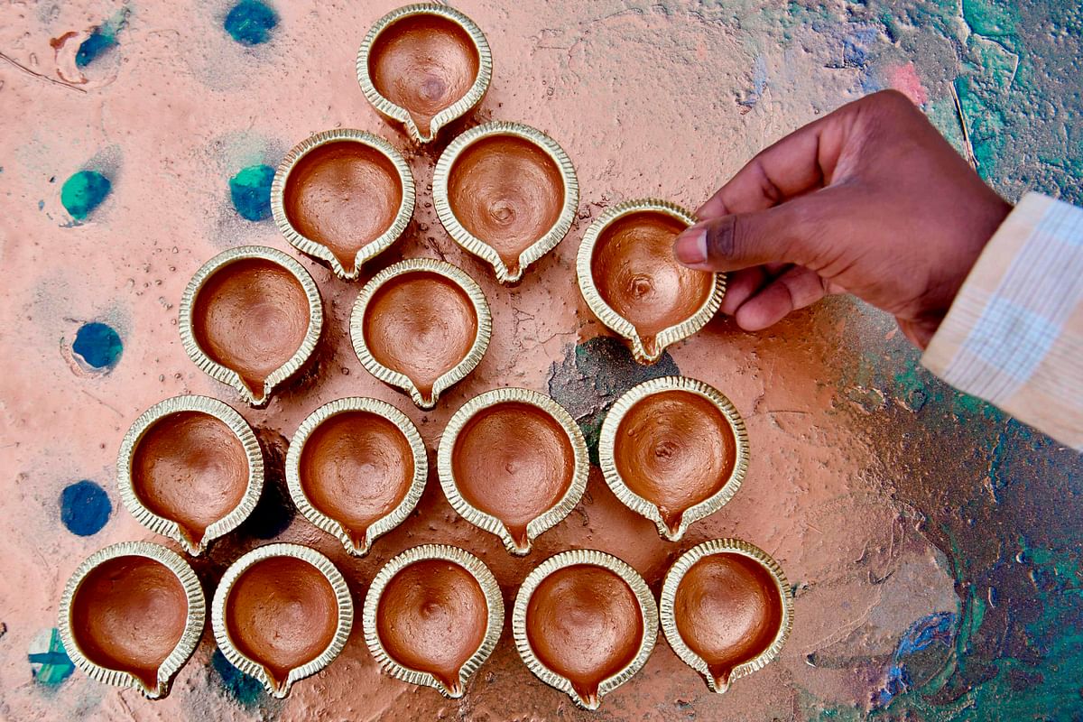 A potter places painted clay oil lamps to dry ahead of Diwali festival, or festival of lights, at Pottery Town in Bangalore on 24 October 2019. Photo: AFP