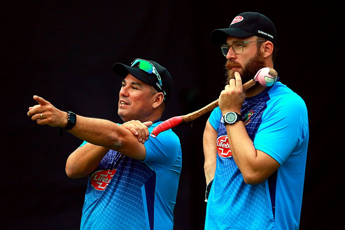 In this handout picture taken and released by Bangladesh Cricket Board (BCB), Bangladesh head coach Russell Domingo (L) and newly joined Bangladesh bowling coach New Zealand former captain Daniel Vettori (C) talk during a training session in Sher-e-Bangla National Cricket Stadium on 25 October 2019. Photo: AFP