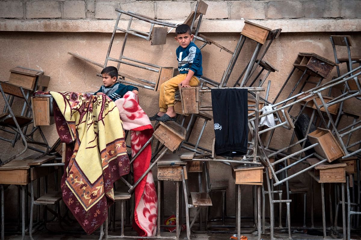 Displaced Syrian children sit on classroom tables at a school turned into a shelter for people displaced by the war, in the northeastern Syrian town of Hasakeh, on 24 October 2019. Photo: AFP