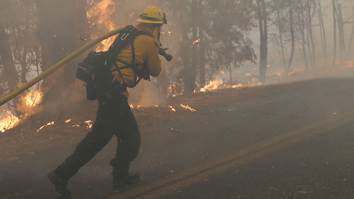 A firefighter pulls a hose along Chalk Hill Road as he battles the wind-driven Kincade Fire in Windsor, California, US on 27 October. Photo: Reuters