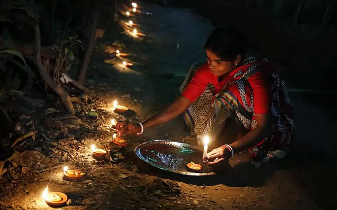 A devotee lights oil lamps on the occasion of Deepabali on her yard in Dhaka`s Bashabo on 27 October, 2019. Photo: Dipu Malakar