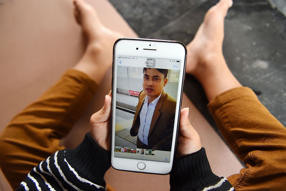 A child looks at a photograph of his 37-year old father Bui Phan Thang, who is feared to be among the 39 people found dead in a truck in Britain, on a mobile phone at their house in Hong Linh district of Vietnam`s Ha Tinh province on 29 October 2019. Photo: AFP