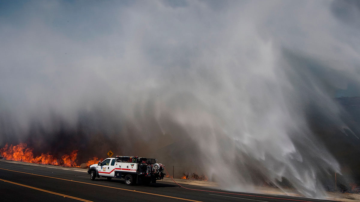 Water dropped by a helicopter lands beside a firefighting vehicle on the road leading to the Reagan Library during the Easy Fire in Simi Valley, California on Wednesday. Photo: AFP