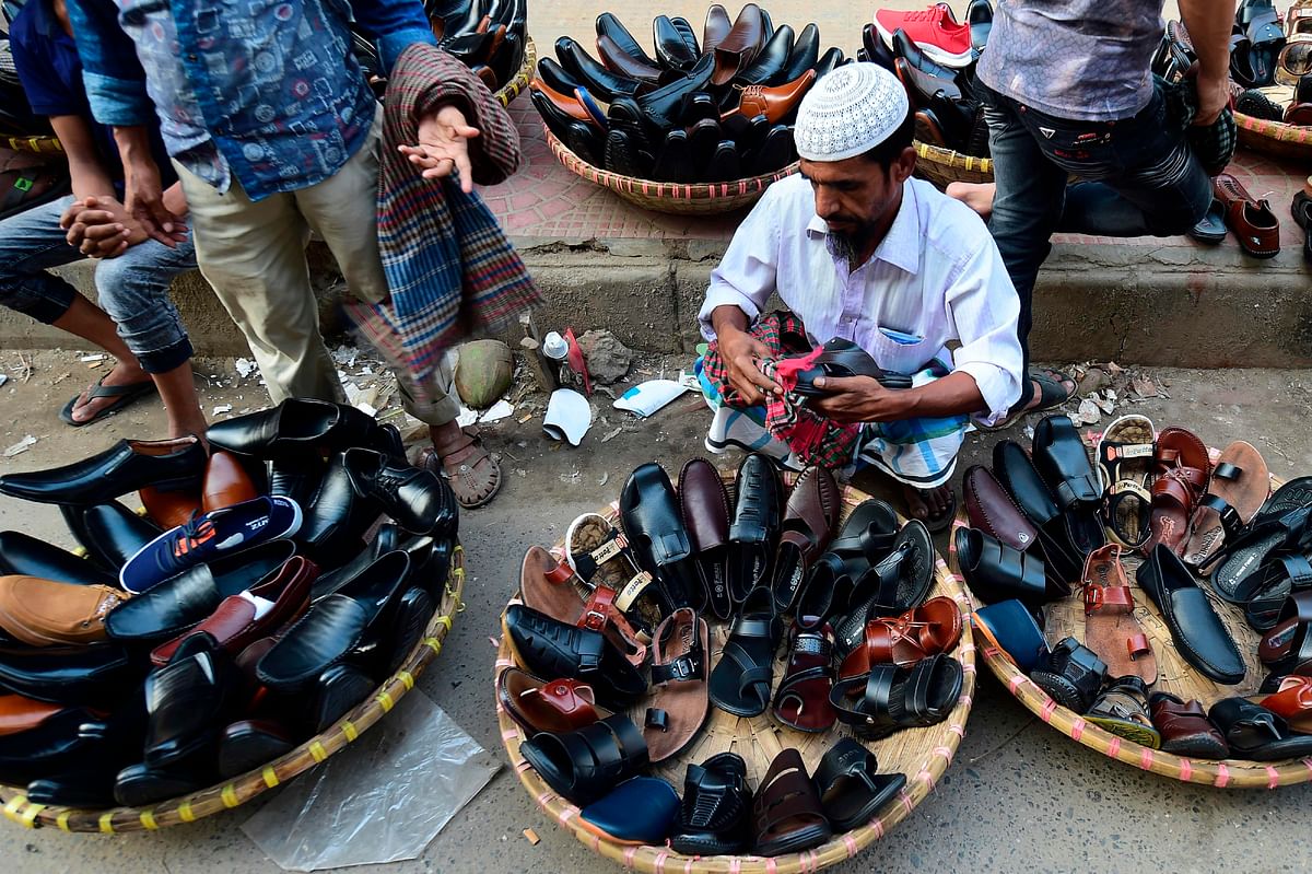 A Bangladeshi street shoe vendors cleans a shoe while waiting for customers in Dhaka on 30 October 2019. Photo: AFP