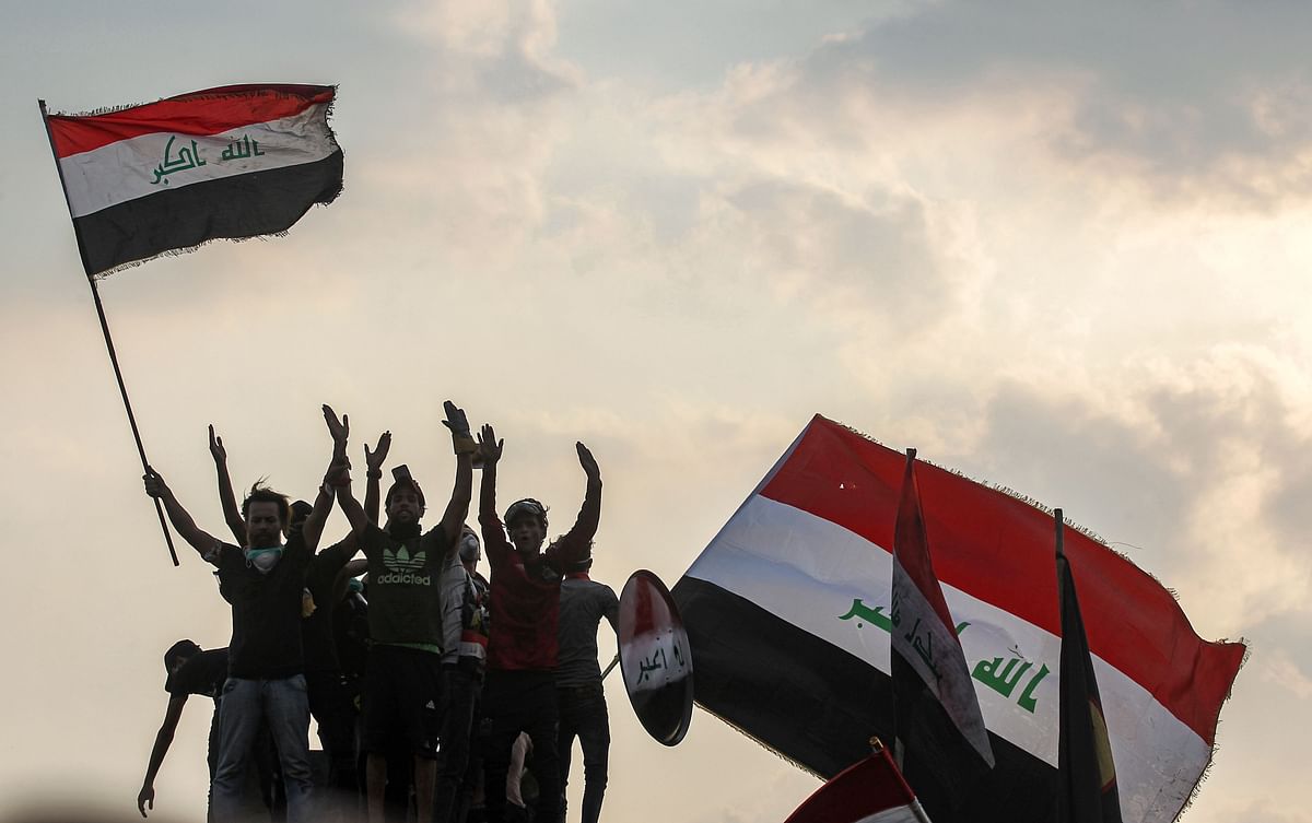 Iraqis wave national flags during a demonstration along al-Jumhuriya bridge leading to the capital Baghdad`s high-security Green Zone, which hosts government offices and foreign embassies, on 29 October 2019 during the ongoing anti-government protests. Photo: AFP