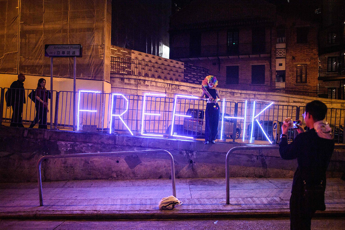 A man takes a photo of a woman as she poses in front of a LED light display in the Central area during Halloween in Hong Kong on 31 October 2019. Hong Kong democracy activists donned Halloween masks lampooning the city`s pro-Beijing leaders n 31 October 2019, defying an emergency law that bans face coverings and sparking renewed clashes with police. Photo: AFP