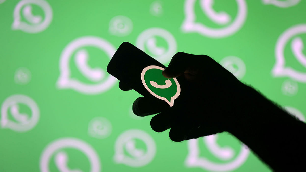 A man poses with a smartphone in front of displayed Whatsapp logo in this illustration. Photo: Reuters