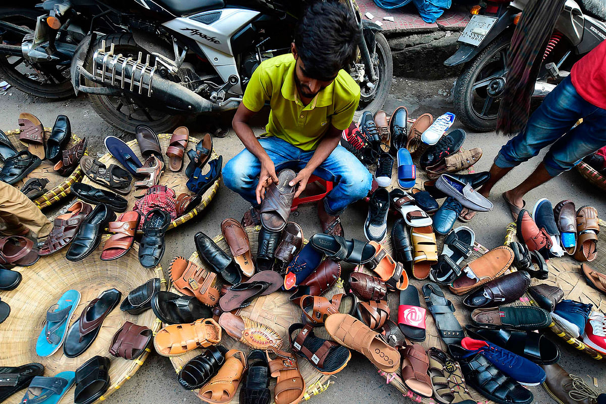 A Bangladeshi street shoe vendor arranges shoes as he prepares his display in Dhaka on 30 October 2019. Photo: AFP
