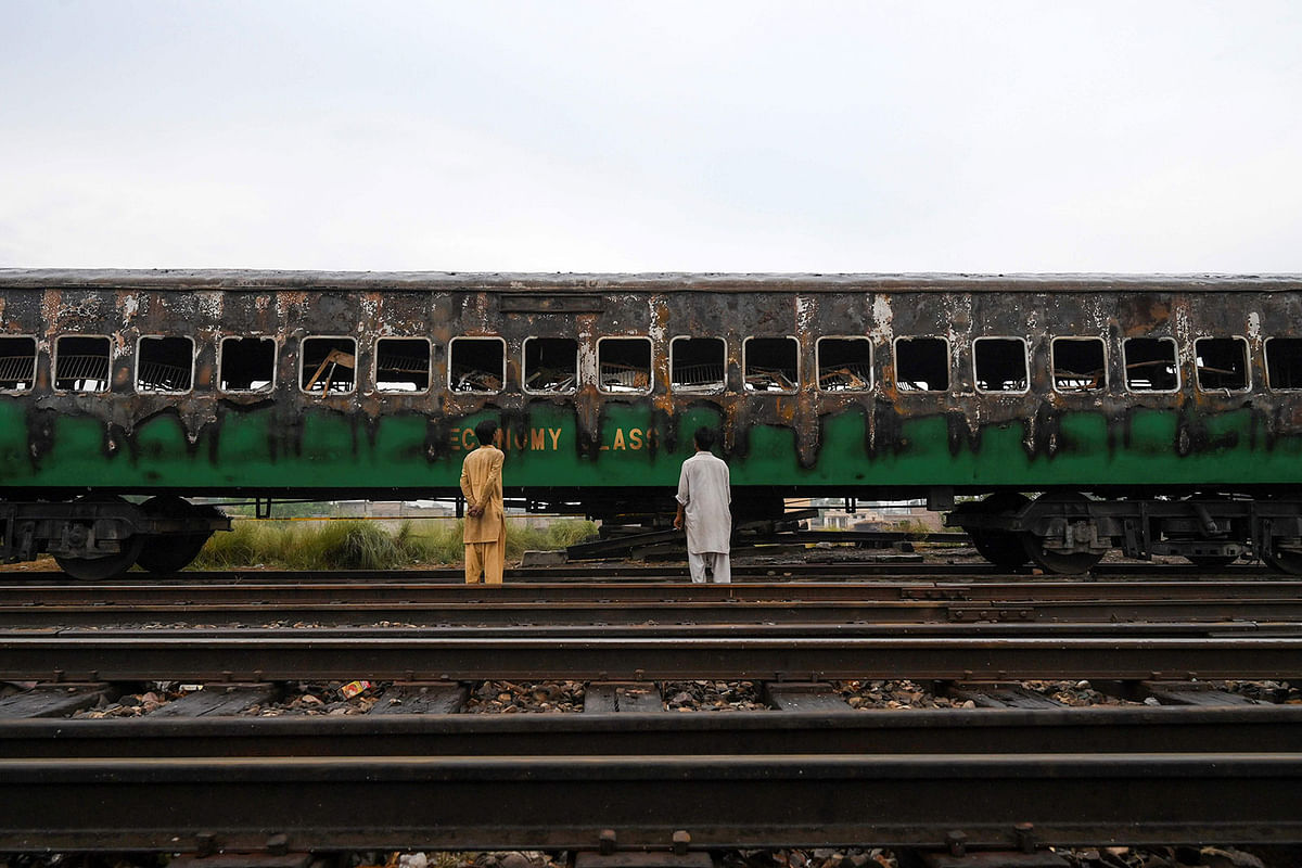People looks at the burnt-out train carriages a day after a passenger train caught on fire in Rahim Yar Khan on 1 November. Photo: AFP
