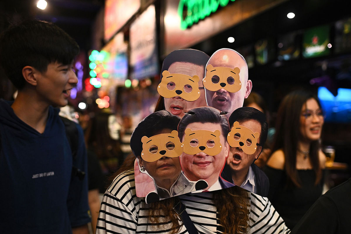 A woman wearing several masks of Hong Kong Chief Executive Carrie Lam (bottom L) and China`s President Xi Jinping (bottom C) marches with others in Central district during Halloween in Hong Kong on 31 October 2019. Photo: AFP