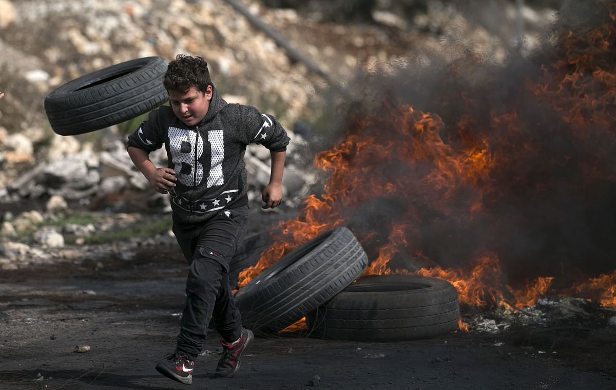 A young Palestinian demonstrator runs near burning tires during clashes with Israeli forces following a weekly protest against the expropriation of Palestinian land by Israel, in the village of Kfar Qaddum, in the Israeli-occupied West Bank on 1 November. 2019. Photo: AFP