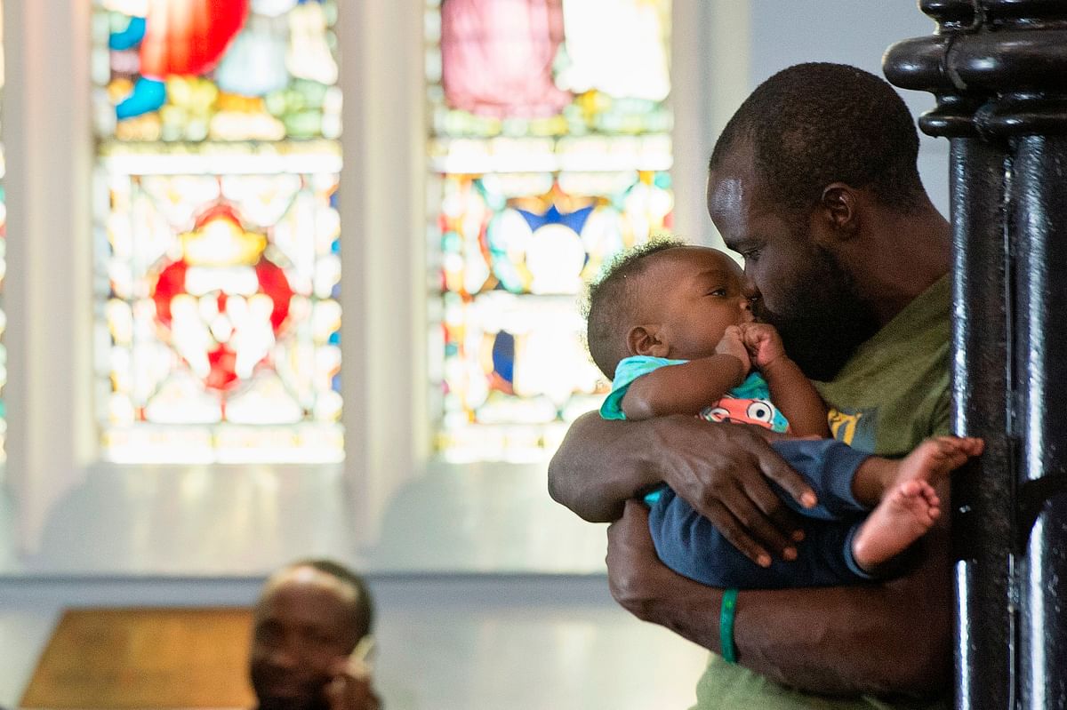 A man kisses a child as hundreds of people, originally from the Democratic Republic of Congo, Rwanda, Burundi, and Bangladesh sleep in the Methodist Church in the city centre after being chased away from a corridor close to the offices of the United Nations High Commission for Refugees(UNHCR), in Cape Town, on 31 October 2019. Photo: AFP