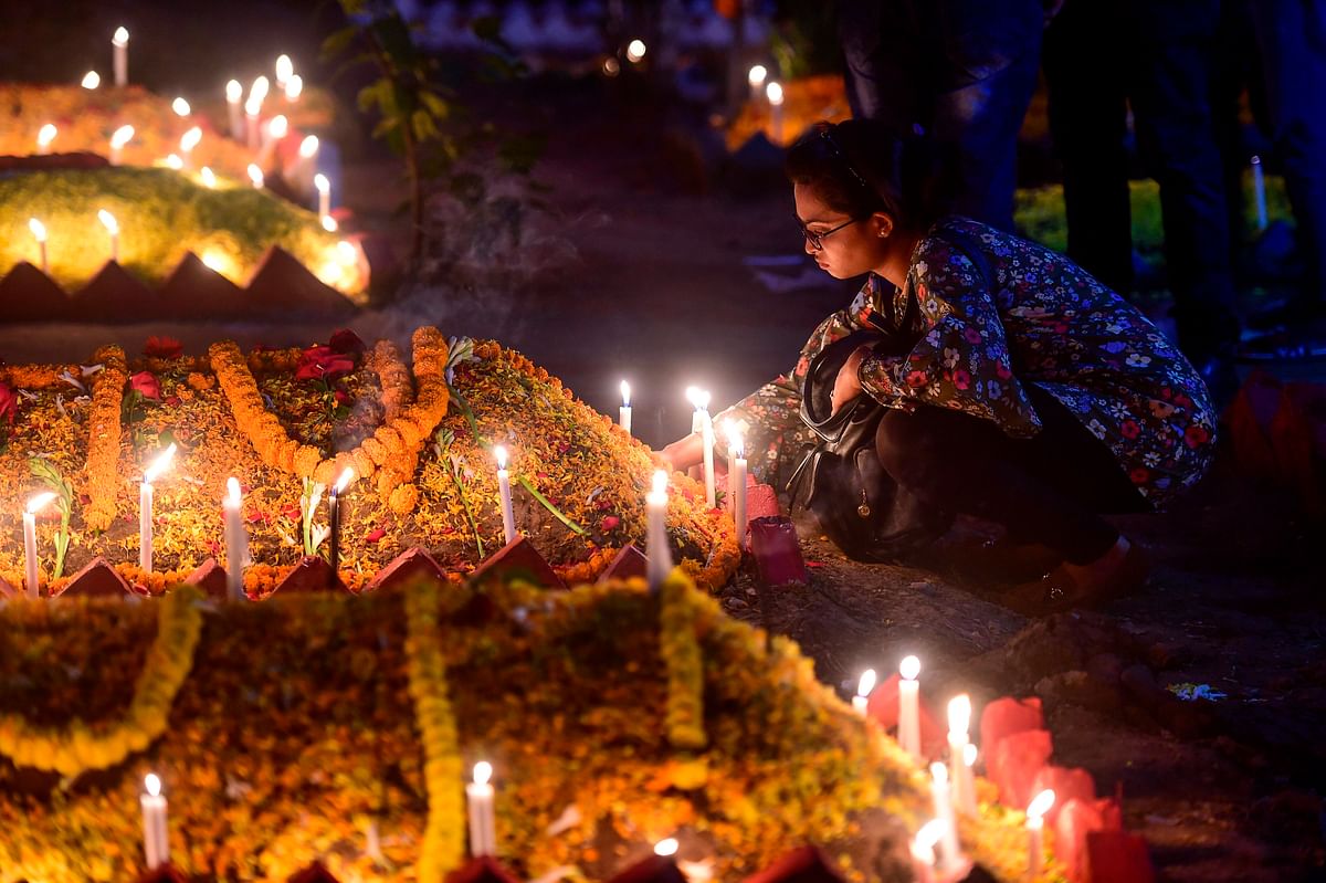 A Christian devotee lights candles on a grave of relatives during the celebrations of All Souls Day in a cemetery in Dhaka on 2 November 2019. Photo: AFP