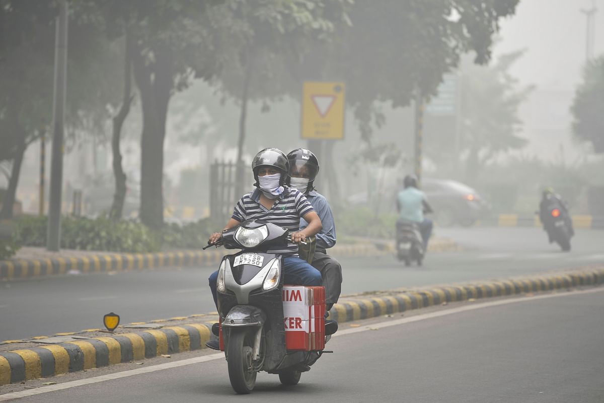 Two wheeler riders wearing a handkerchief to cover their faces ride along a road under heavy smog conditions, in New Delhi on 3 November 2019. Photo: AFP