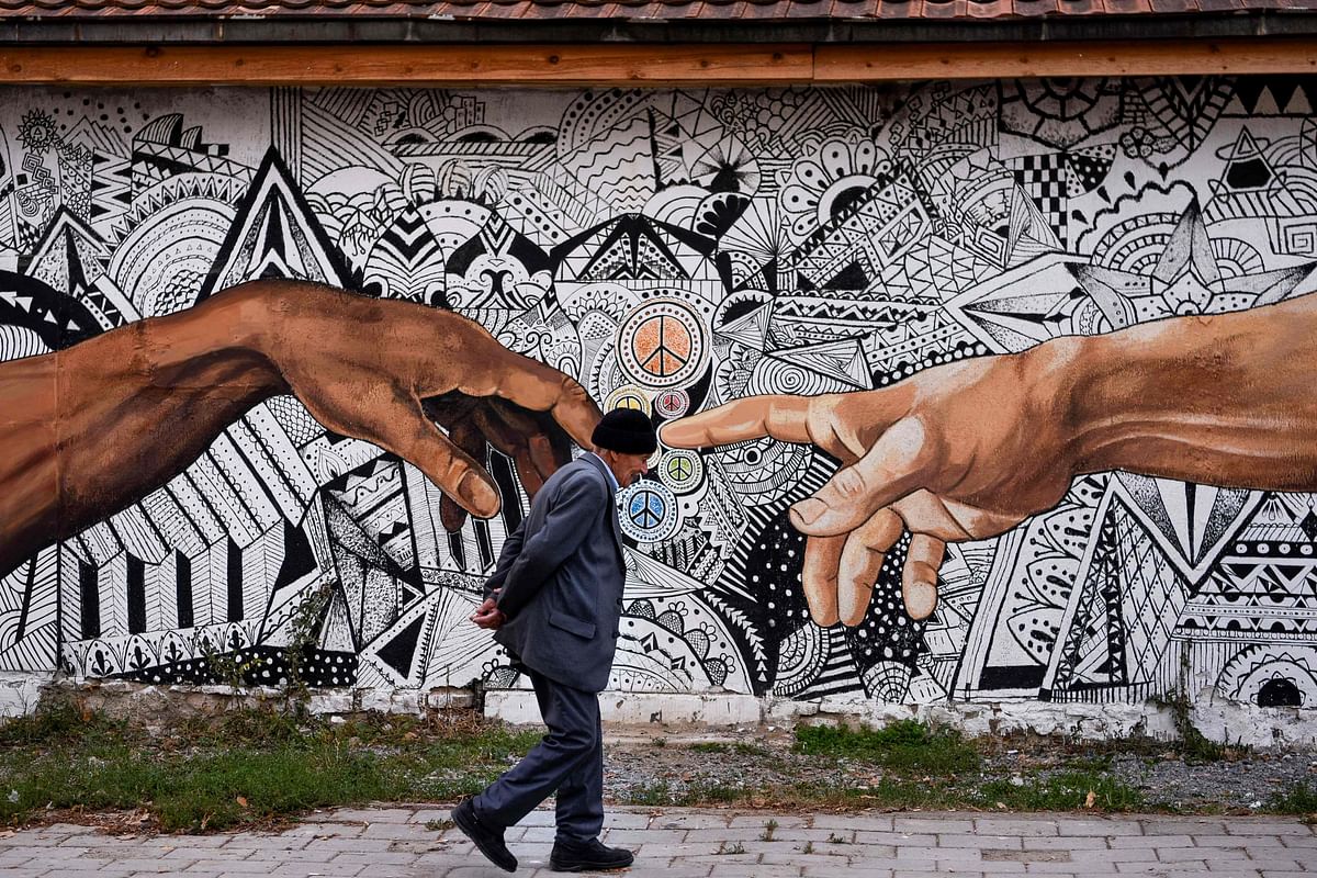 A pedestrian walks past a mural artwork painted on the wall of a house in the town of Ferizaj on 3 November 2019. Photo: AFP