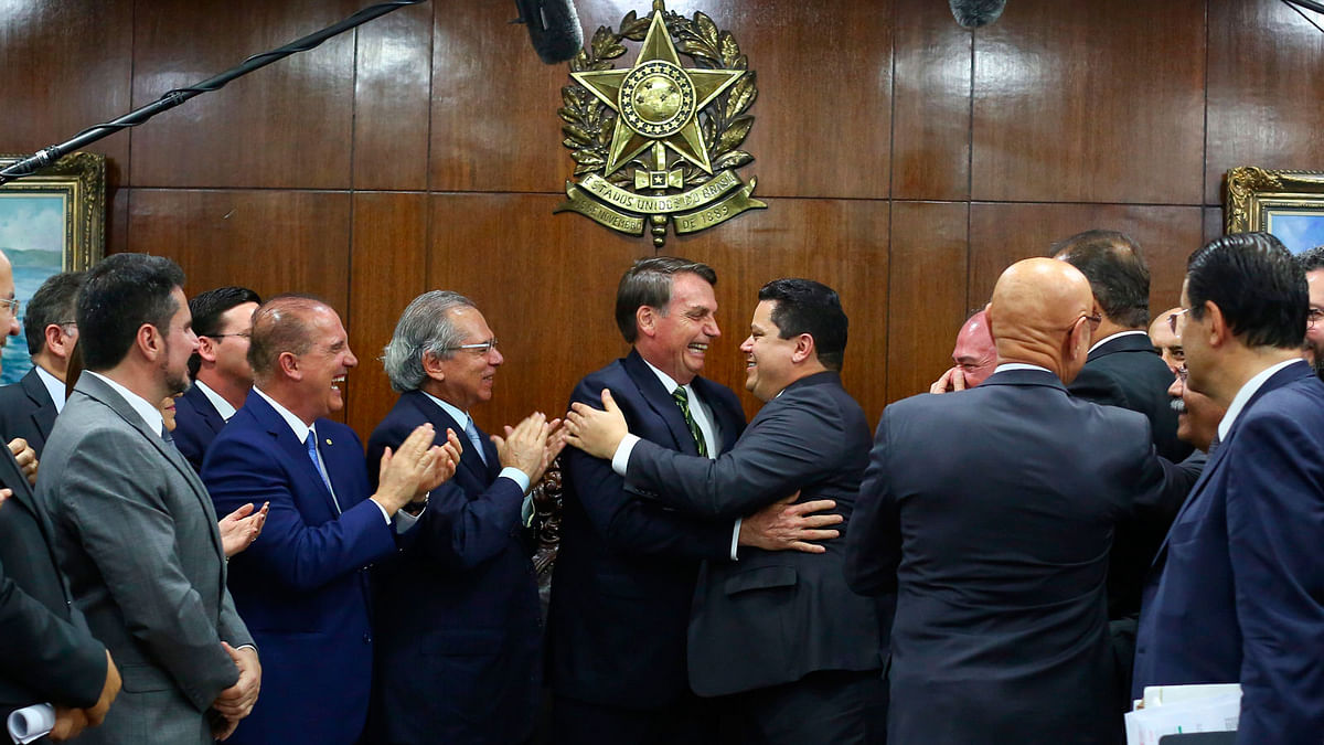 Brazilian president Jair Bolsonaro (2-R), shakes hands with the president of the senate Davi Alcolumbre, as his economy minister Paulo Guedes (C-L) applauses during the delivery of the economic reform package to the National Congress in Brasilia, Brazil on 5 November. Photo: AFP