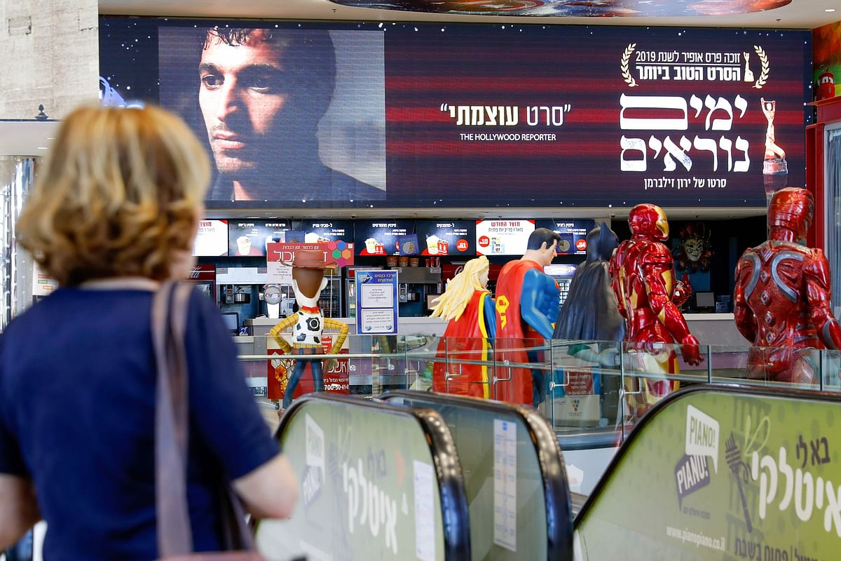 Israelis walk past posters for the movie `Incitement,` at a cinema complex in the Israeli coastal city of Netanya, on 4 November. Photo: AFP