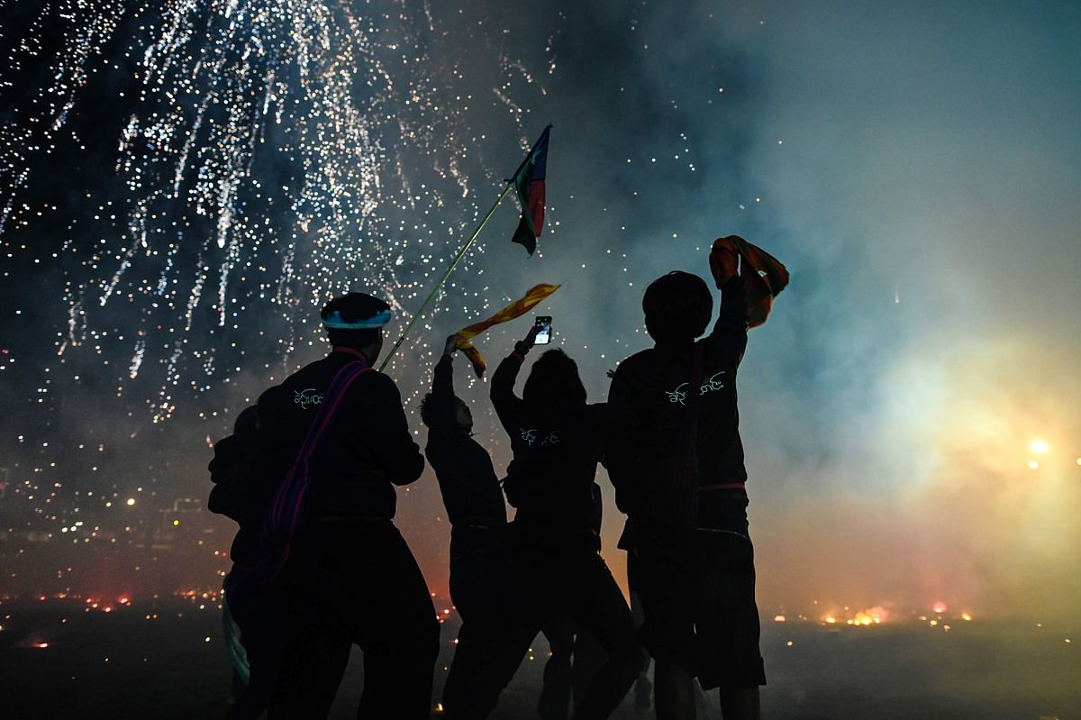 his picture taken on 5 November 2019 shows participants celebrating as fireworks explode after they released a hot-air balloon attached with fireworks during the Tazaungdaing Lighting Festival at Taunggyi in Myanmar`s northeastern Shan State. Photo: AFP