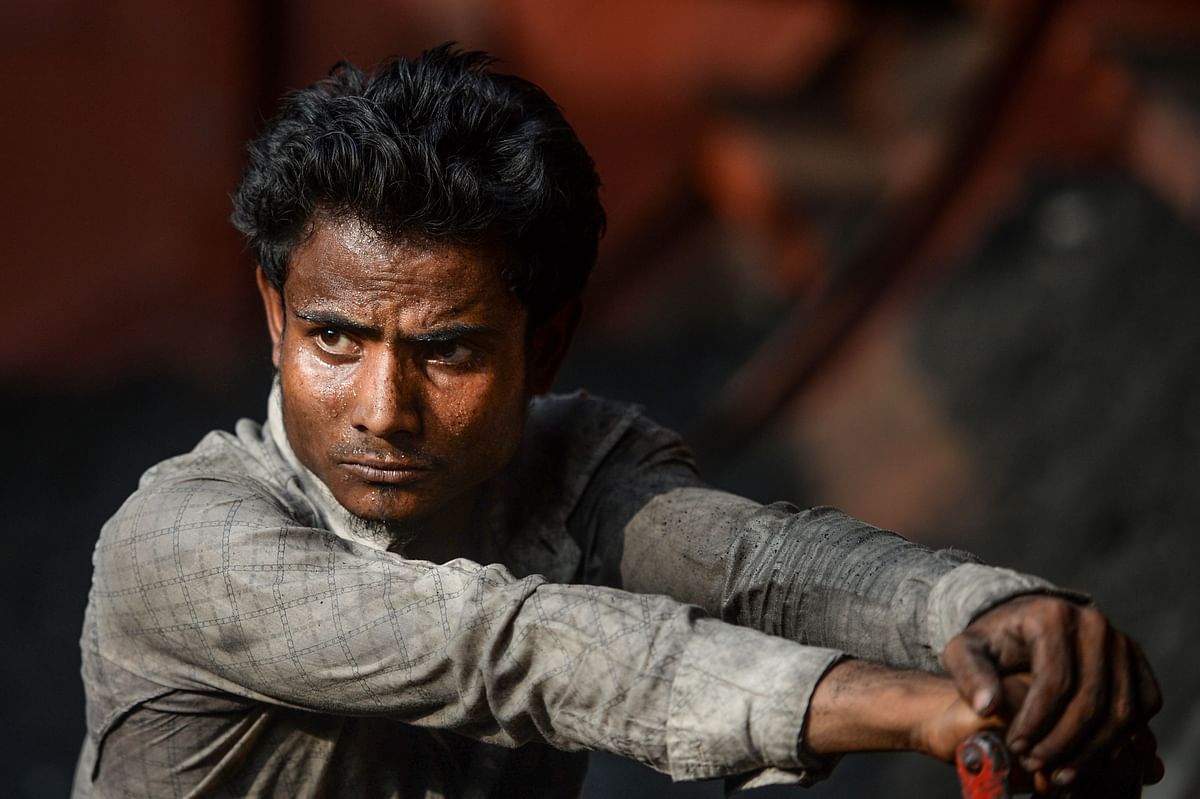 A labourer looks on as he unloads coal from a cargo ship in Gabtoli on the outskirts of Dhaka on 6 November 2019. Photo: AFP