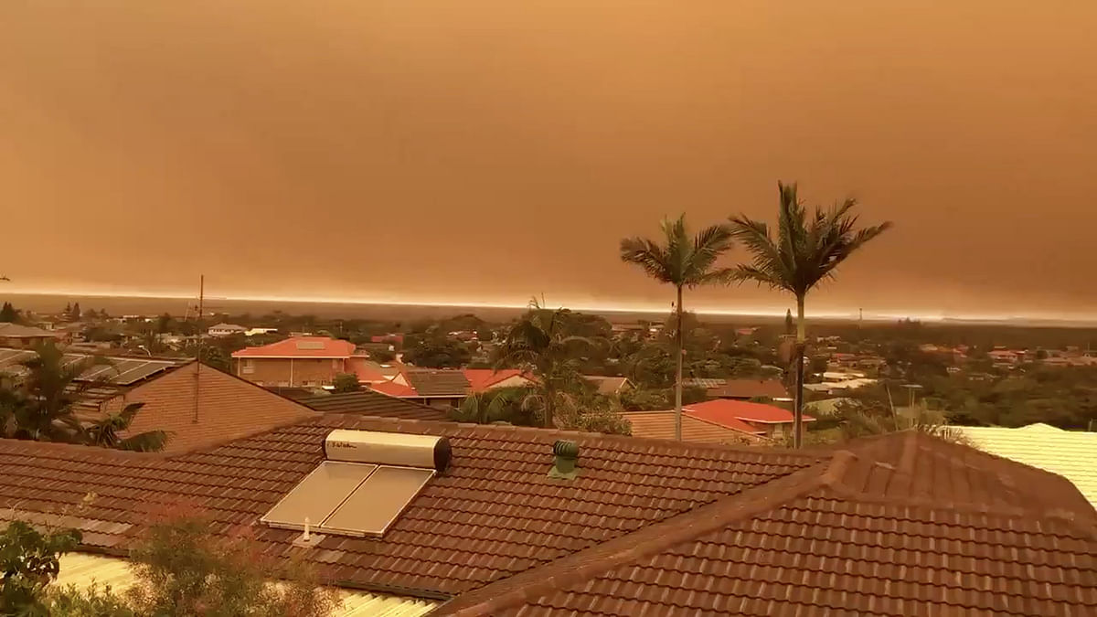 Smoke with orange tint blanketing skies and orange hues are seen from a kitchen window in Port Macquarie. Photo: Reuters
