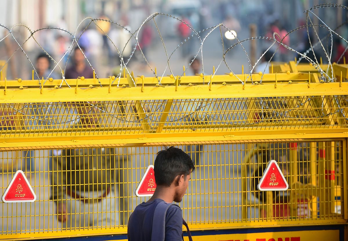 A man walks past a police road block fence with barbed wire on top in Ayodhya on 9 November 2019, ahead of a Supreme Court verdict on the disputed religious site. Photo: AFP